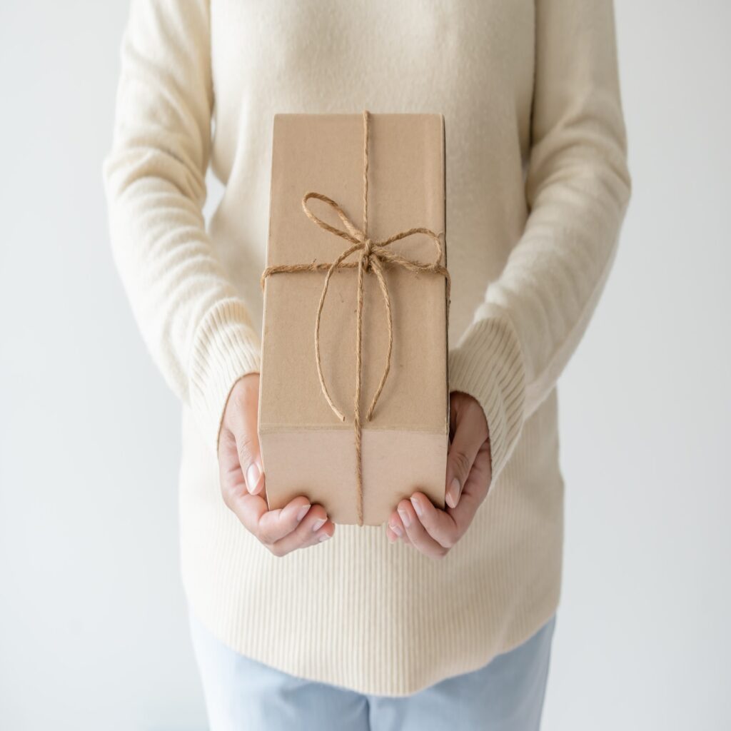 Woman hands holding present box with a ribbon bow. Minimalist concept of giving a present.
